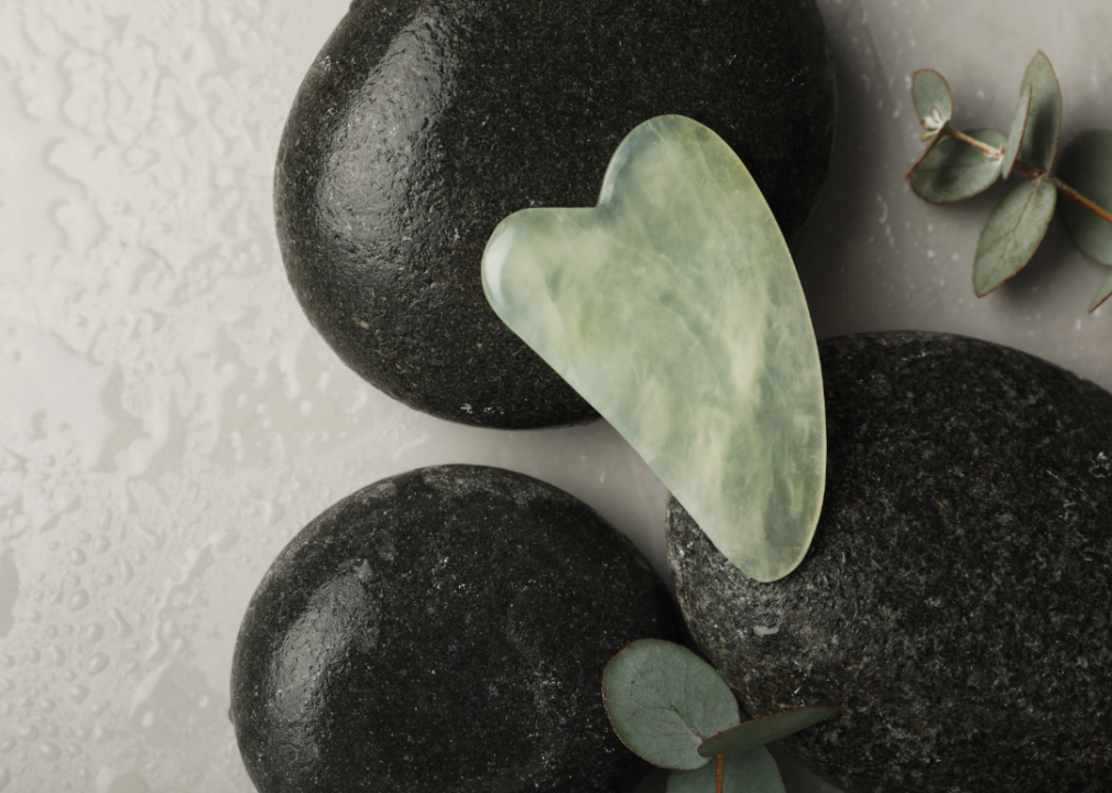The truth behind 5 unconventional self-care rituals that have gone viral on TikTok jade color gua sha tool displayed on black stones